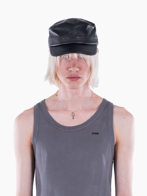 Model wearing a black VAIN lamb leather cap with a star-shaped deboss and logo stitching on the visor.