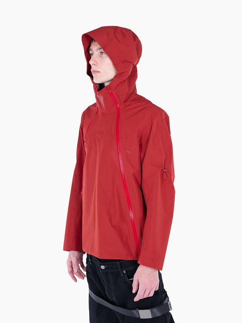 A model wearing a red VAIN shell jacket with a heart-shaped yoke, asymmetrical waterproof zipper, and hood.
