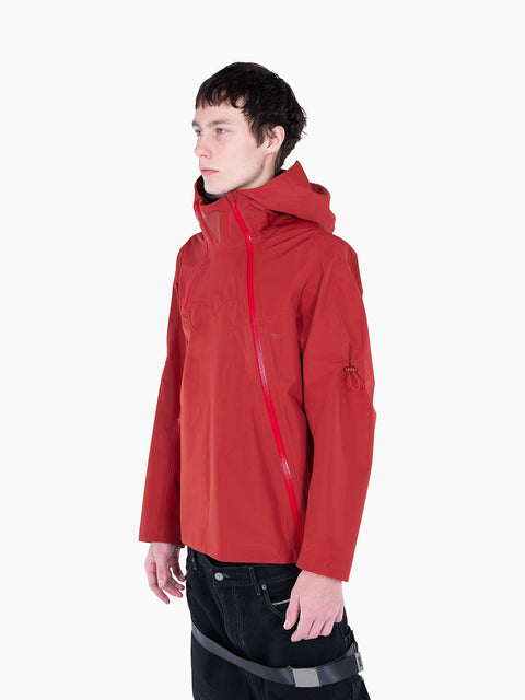 Model wearing a red VAIN shell jacket with asymmetrical waterproof zipper, heart-shaped yoke, and hood.