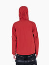 Back view of a red VAIN shell jacket with a heart-shaped yoke, hood, and waterproof zipper, worn by a model.